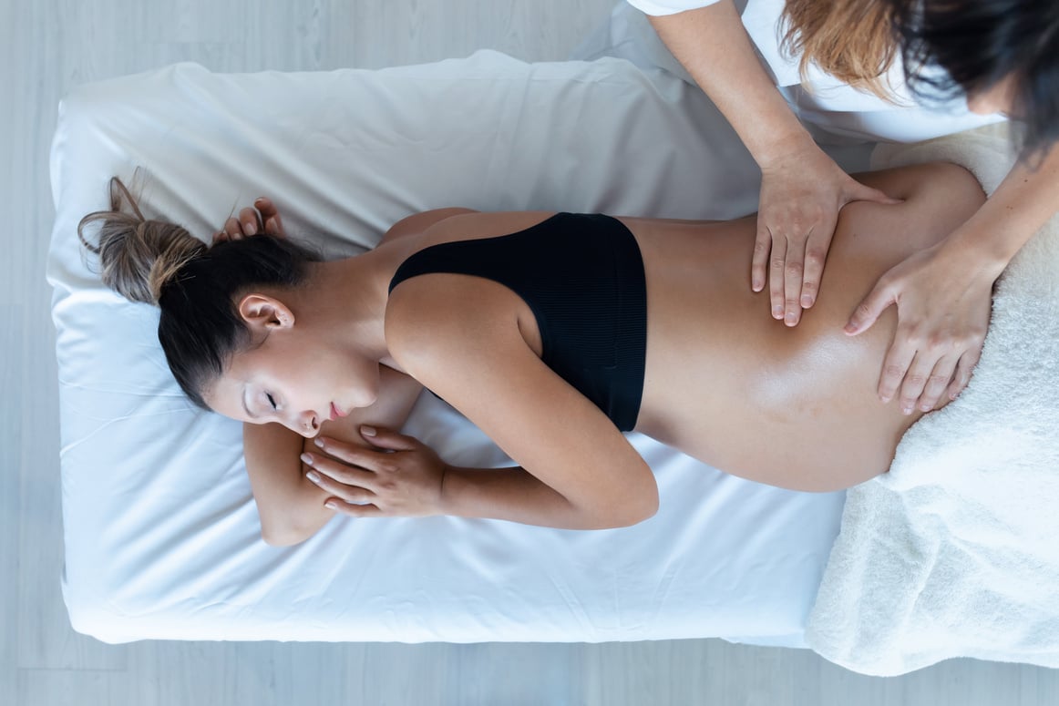 Beautiful Young Physiotherapist Woman Massaging Tummy on Pregnan